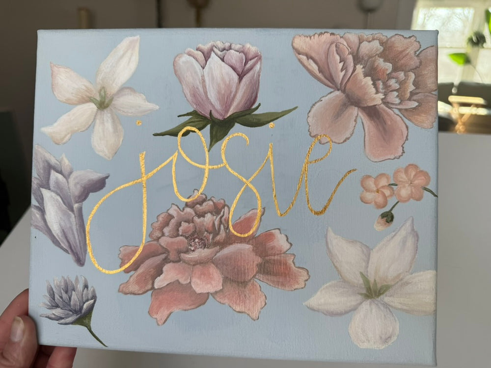 Nursery name sign reading Josie, surrounded by hand-painted flowers